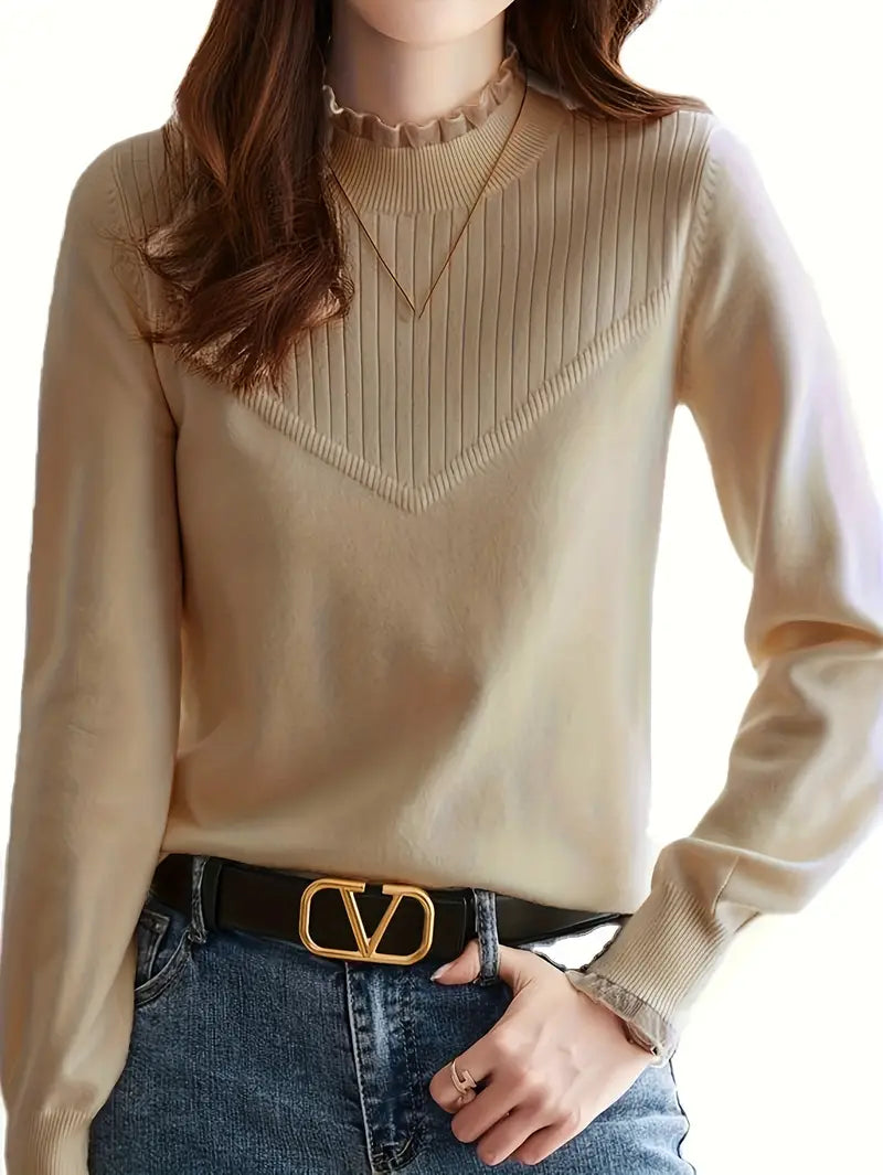 Une personne porte le « Pull en tricot à bords élégants pour un look chic et confortable » de la marque Olivia's Boutique en beige, associé à un jean bleu. Cet ensemble élégant est accessoirisé d'un collier doré et d'une ceinture noire à boucle dorée.