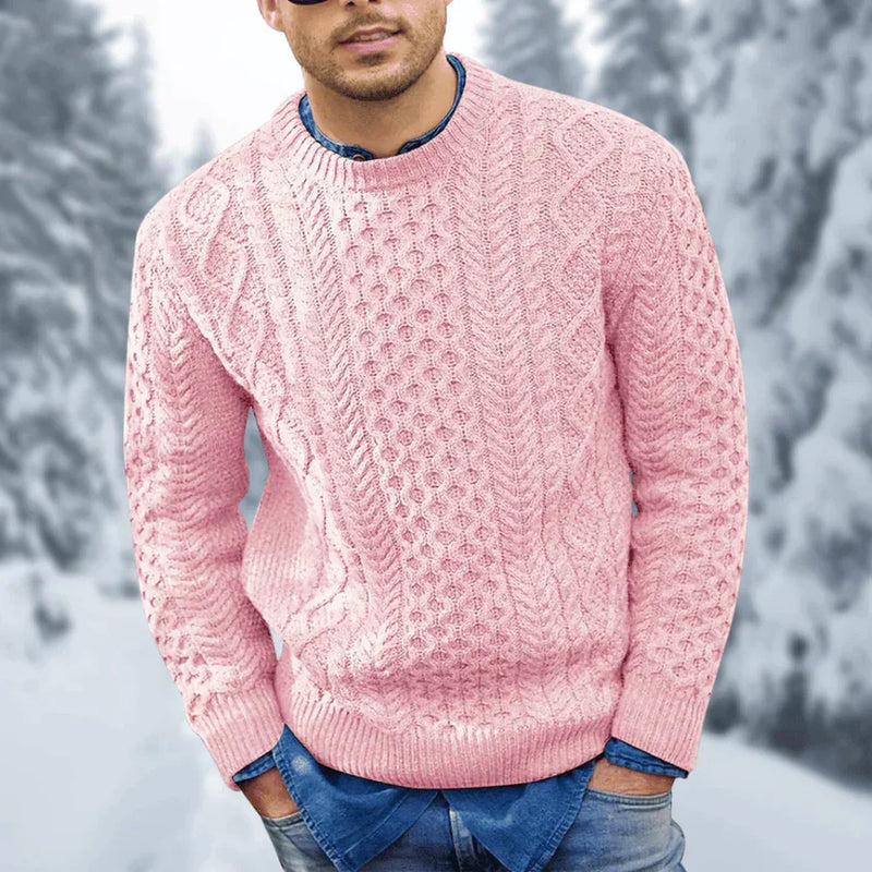 Une personne portant le « Branimir - Eleganter Pullover mit langen Ärmeln » d'Olivia's Boutique en rose texturé sur une chemise en jean se tient dans un décor extérieur enneigé, avec des conifères flous en arrière-plan.