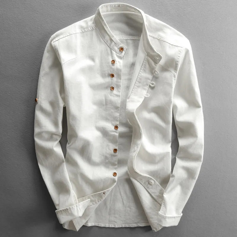 Une « Chemise élégante et confortable pour tous les jours » d'Olivia's Boutique est présentée à plat sur un fond gris. Cette chemise blanche à manches longues et col mao avec boutons marron présente un design boutonné double épaisseur unique sur un côté et des poignets boutonnés élégants, offrant à la fois élégance et polyvalence pour toutes les occasions.