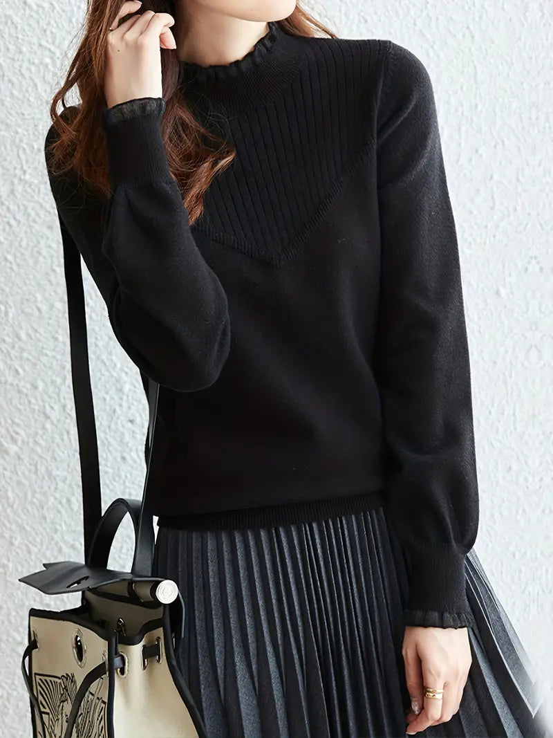 Une personne vêtue d'un pull en tricot à bords élégants pour un look chic et confortable d'Olivia's Boutique, doté d'un décolleté haut, associé à une jupe plissée foncée, porte un sac à main crème avec une bandoulière noire et un design tendance. La scène se déroule sur un fond à texture claire.