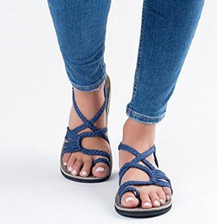 Une personne porte un jean bleu et des « Sandales de Plage Colorées » d'Olivia's Boutique, mettant en valeur des ongles de pieds manucurés sur un fond blanc. Parfait pour toute sortie ensoleillée, cet ensemble élégant capture l'essence des chaussures d'été et du denim.